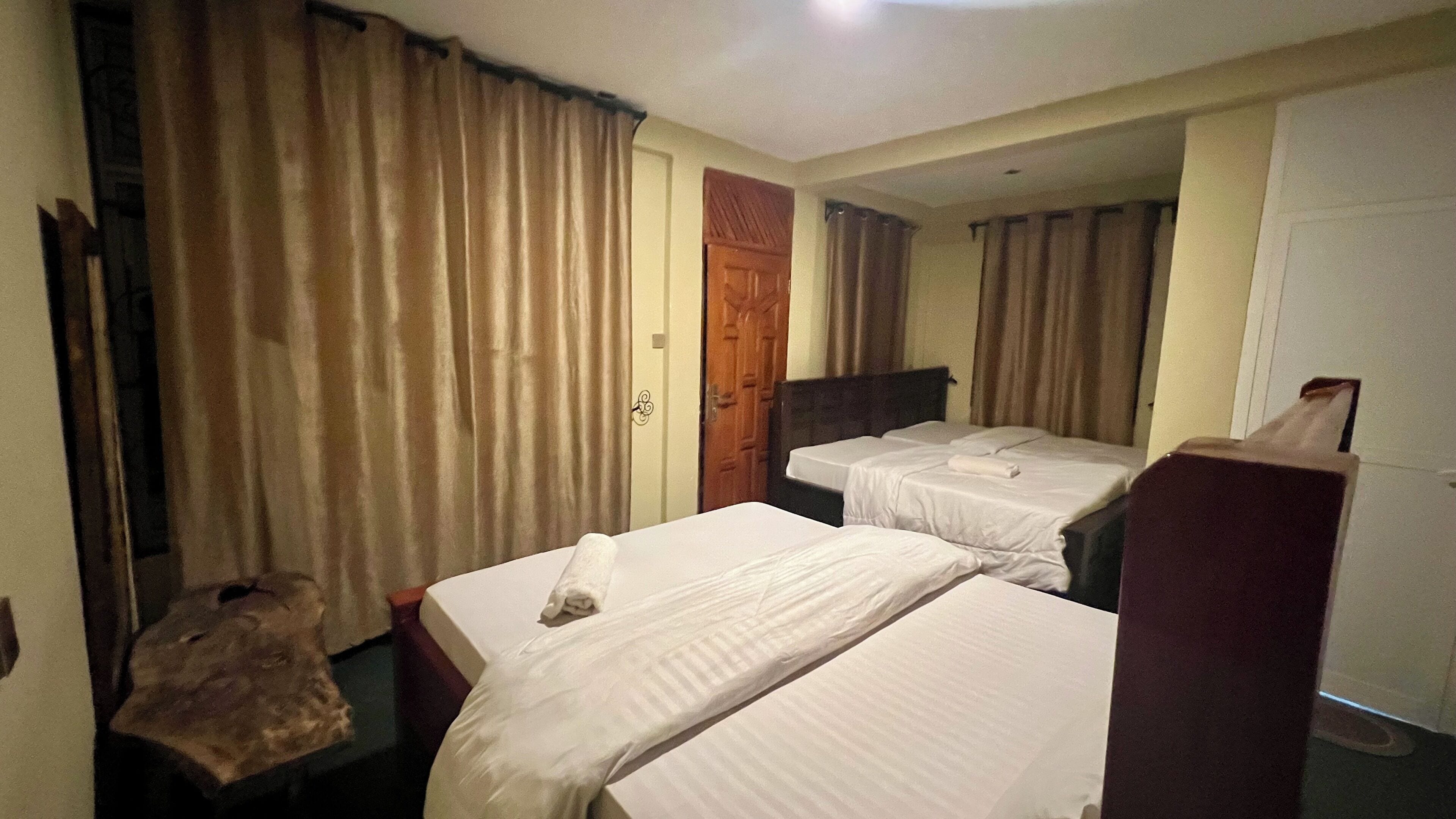 Una habitación de hotel con dos camas individuales, una puerta de madera y una mesita.