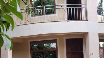A two-story building with a balcony, a large window, and a door.