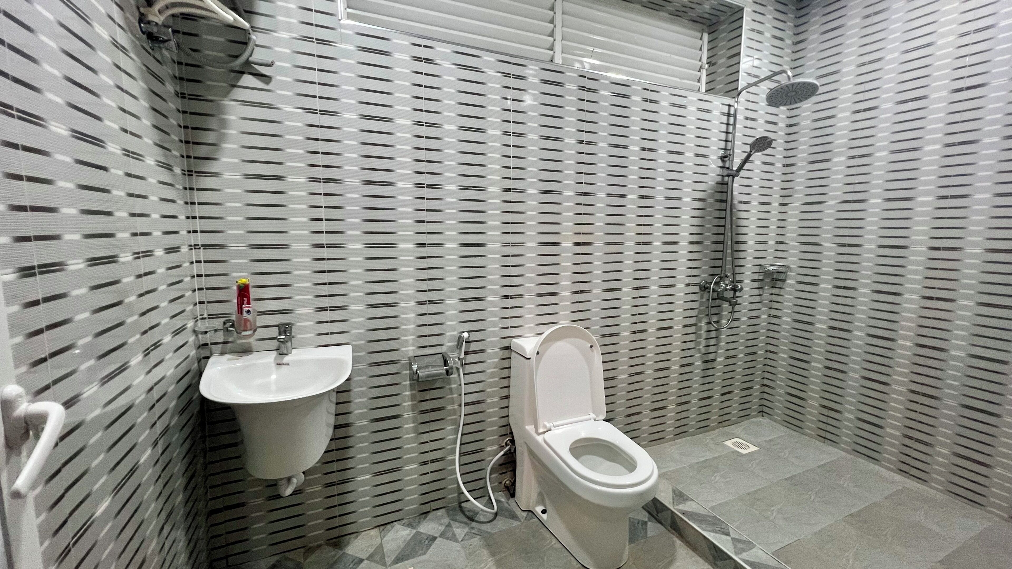 A bathroom with a toilet, sink, and shower.