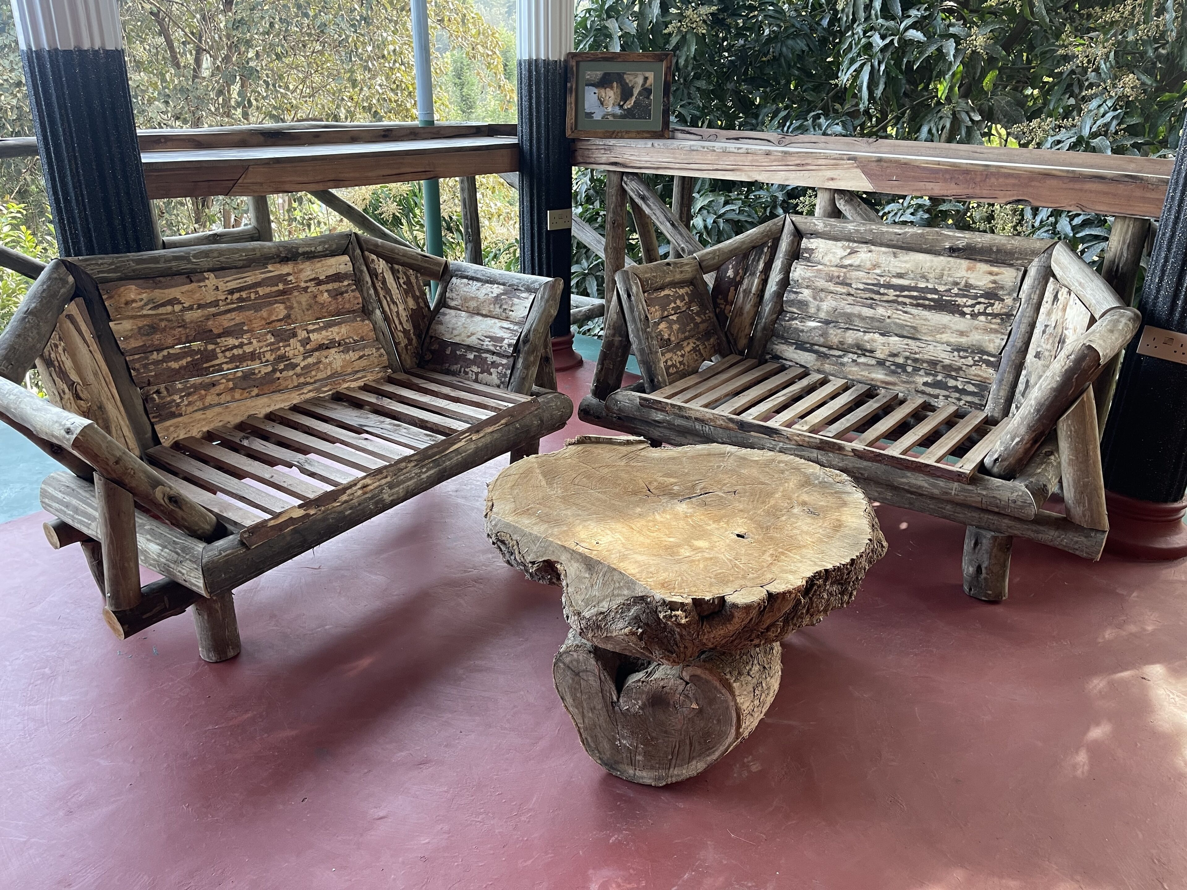 Two rustic wooden benches with slatted seats and backrests, a central wooden table with a natural finish, and a framed picture on the wall.