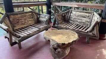 Two rustic wooden benches with slatted seats and backrests, a central wooden table with a natural finish, and a framed picture on the wall.