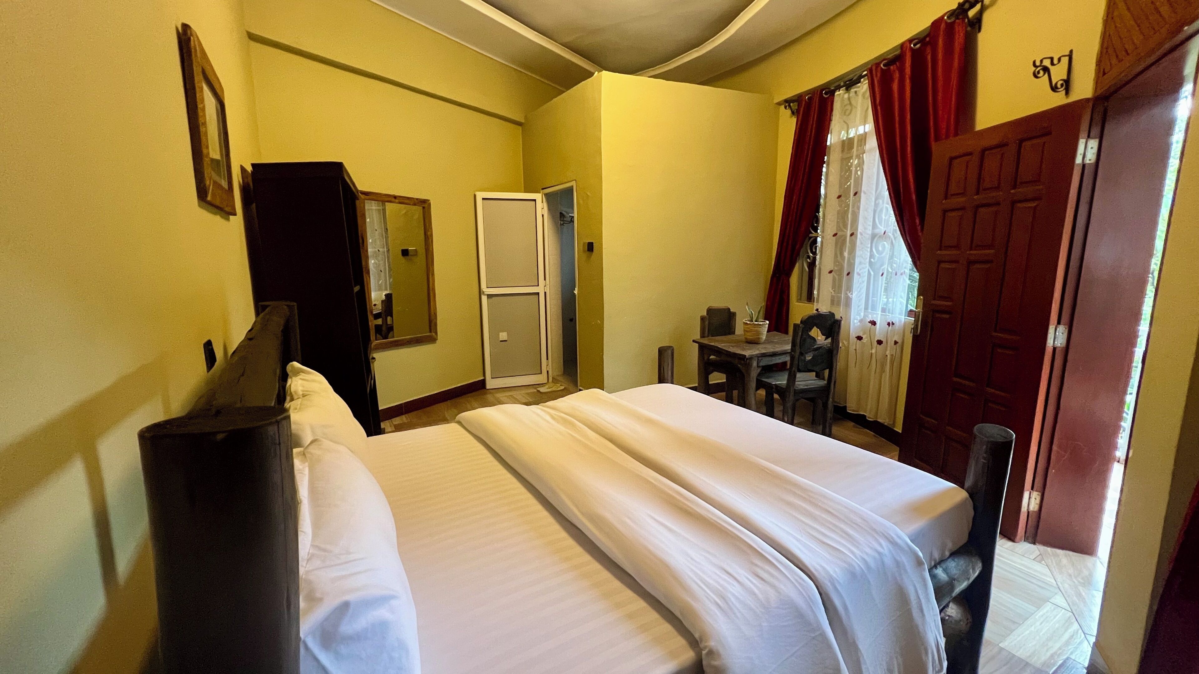 Een hotelkamer met een bed, een bureau, een stoel, een kast en een deur.