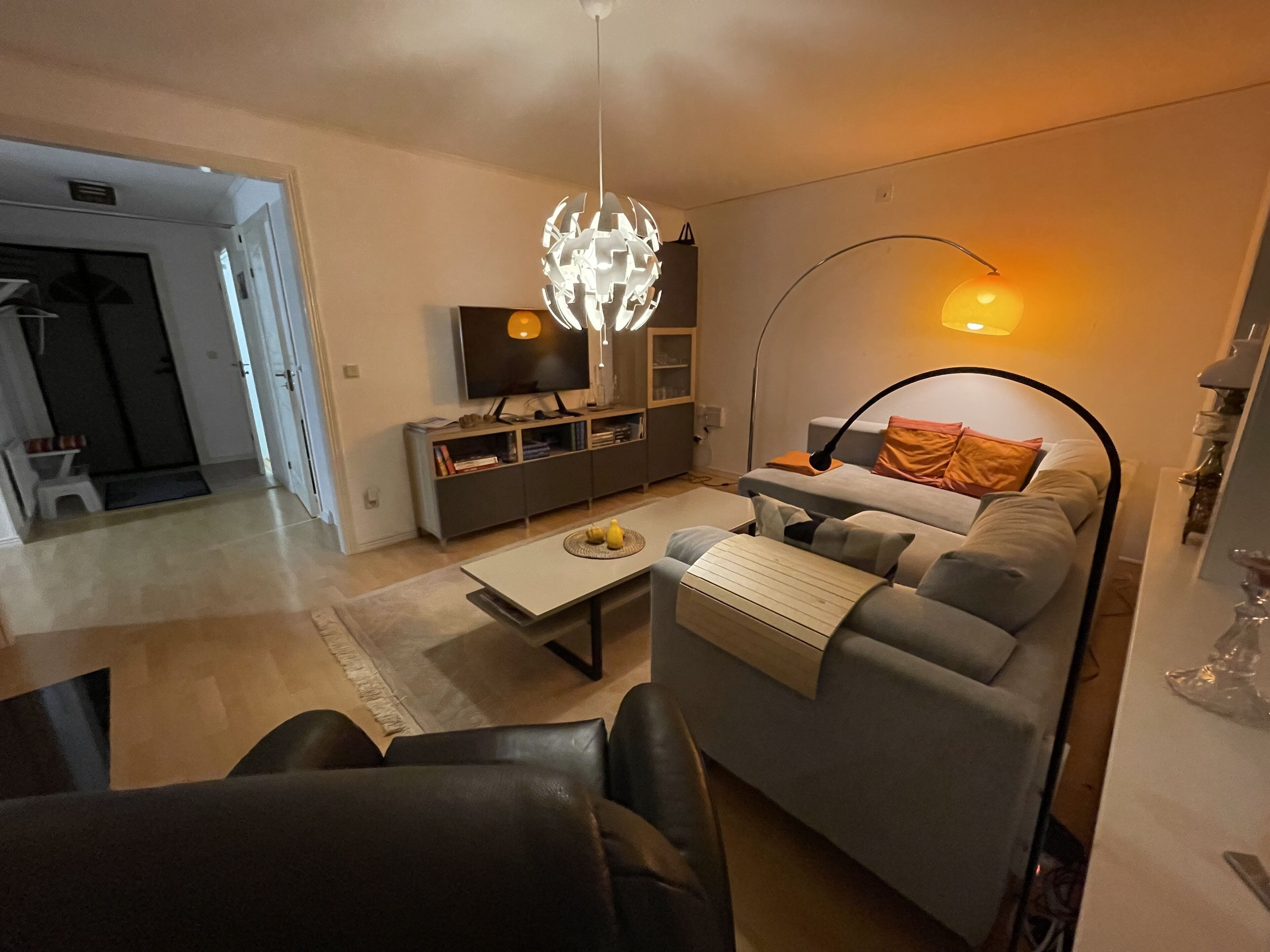 Ein modernes Wohnzimmer mit grauem Sofa, Couchtisch und Fernseher auf einem Schrank.