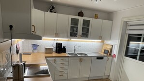 A modern kitchen with white cabinets, a wooden countertop, a sink, and a coffee maker. - Haus am See (Älmeboda)