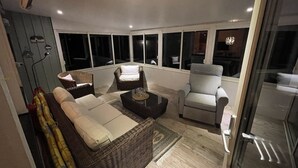 A modern living room with a sofa, armchairs, and a coffee table. Large windows provide a view of the outside. - Haus am See (Älmeboda)