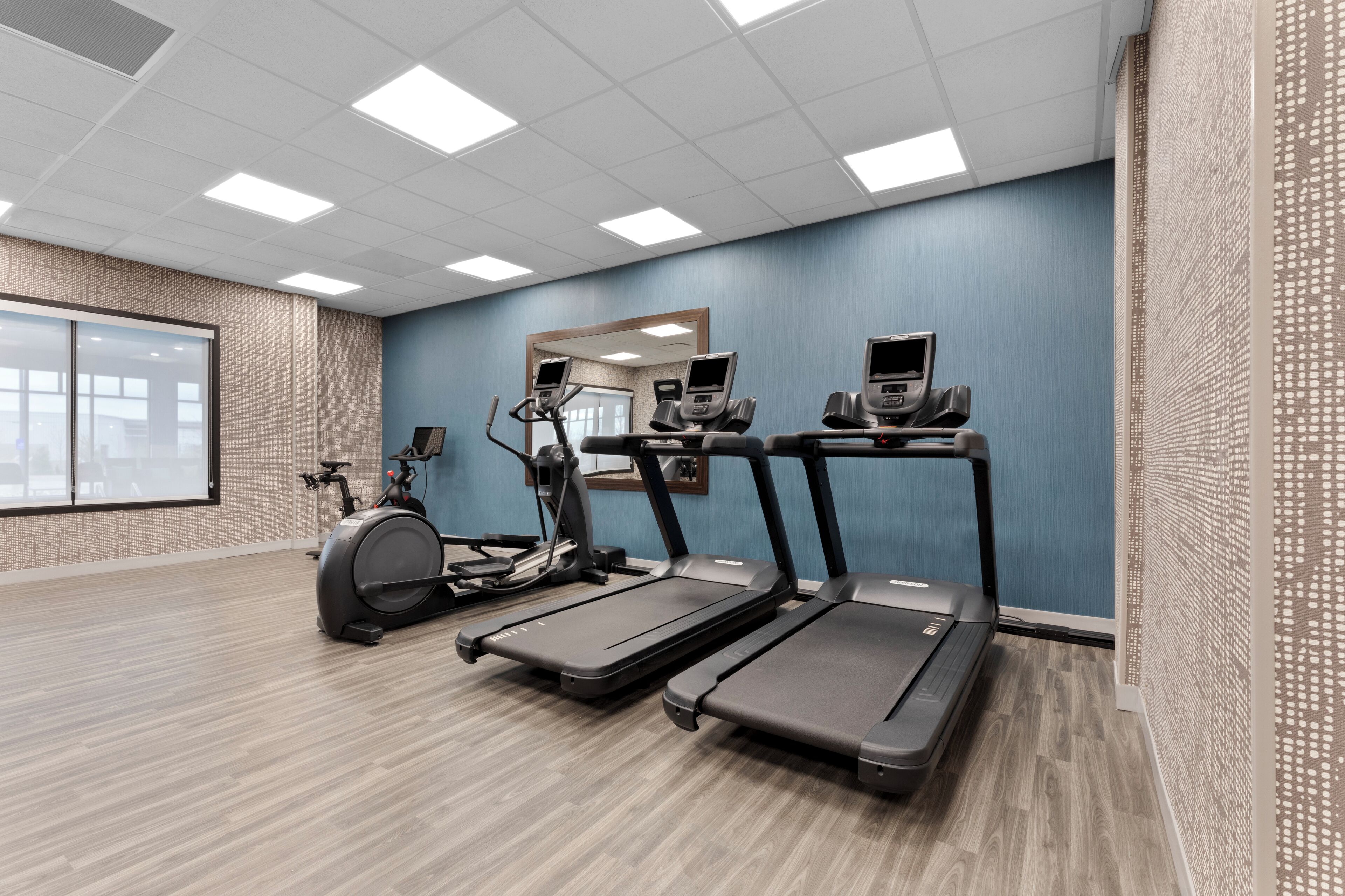 A fitness room with treadmills, an elliptical, and a stationary bike.
