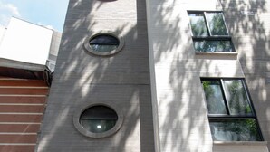 En modern byggnad med en framträdande skylt som visar texten ”81 Tower”, en trappa av betongsteg som leder till en svart dörr och flera fönster.