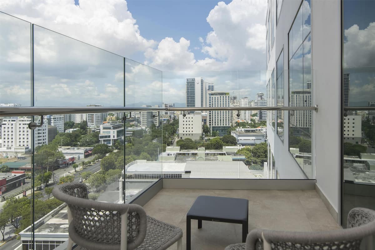 A balcony with a view of a cityscape, including buildings and trees.