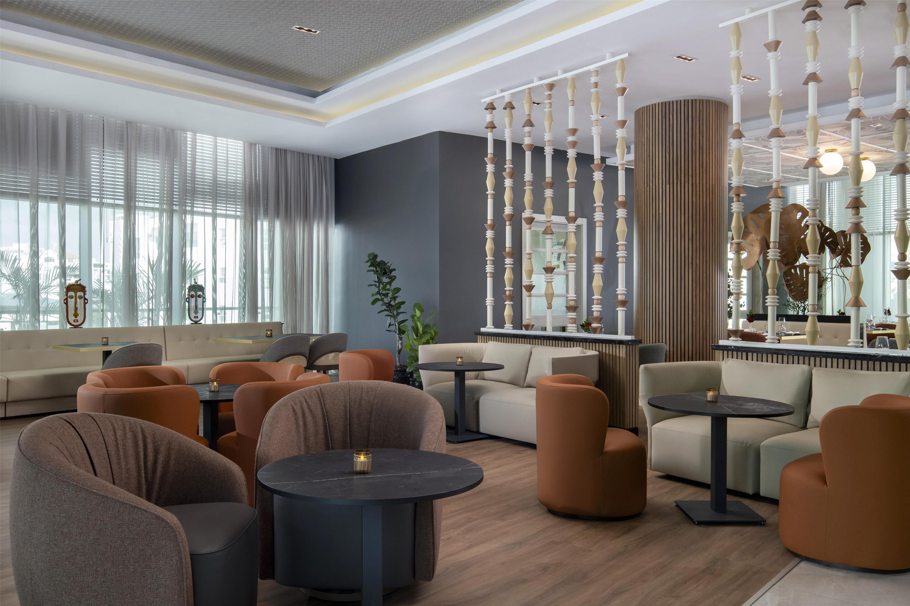 Un espace de détente moderne, avec des canapés, des fauteuils et des tables rondes.