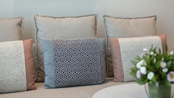 Un divano con cuscini decorati, un quadro incorniciato e un piccolo tavolino con un vaso.