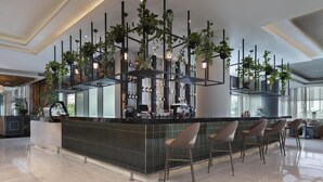 A modern bar area with a central island, bar stools, and hanging plants.