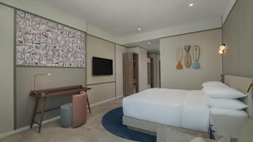 Une chambre d’hôtel moderne dotée d’un grand lit, d’un bureau, d’une chaise, d’une télévision et d’œuvres d’art décoratives au mur.