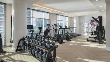 Un gimnasio moderno con cintas de correr, elípticas y pesas libres.