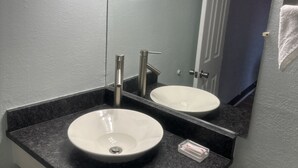 A bathroom with two sinks, a mirror, and a towel rack. - Whispering Pines Motel (Asheville)