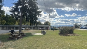 A motel with outdoor picnic tables and a stone fire pit. - Whispering Pines Motel (Asheville)