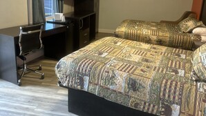 A bedroom with a bed, a desk, a chair, a television, and a window with curtains. - Whispering Pines Motel (Asheville)