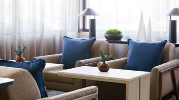 A modern hotel room with a sofa set, a small table, and a potted plant.