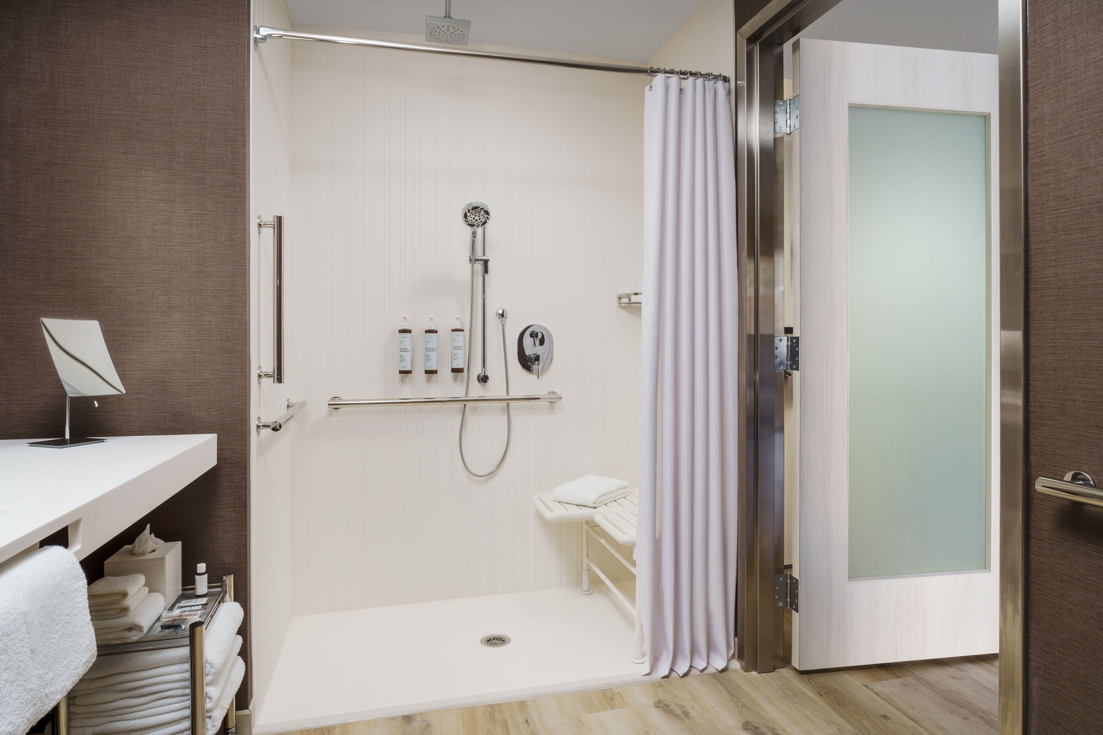 Un bagno moderno con doccia a pavimento, porta doccia in vetro e porta asciugamani bianca.