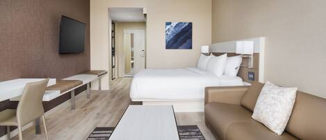 Una habitación de hotel moderna con cama, sofá, escritorio y televisor.