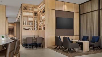 A modern living room with a flat-screen TV, a dining area with a table and chairs, and a seating area with sofas and a coffee table.