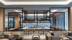 Zona de bar moderna con asientos, una barra y vistas a la ciudad a través de amplios ventanales.