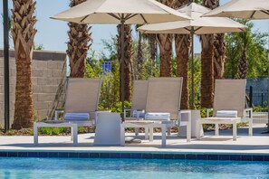 A poolside area with lounge chairs and umbrellas, surrounded by palm trees. - AC Hotel Jacksonville St Johns Town Center (Jacksonville)