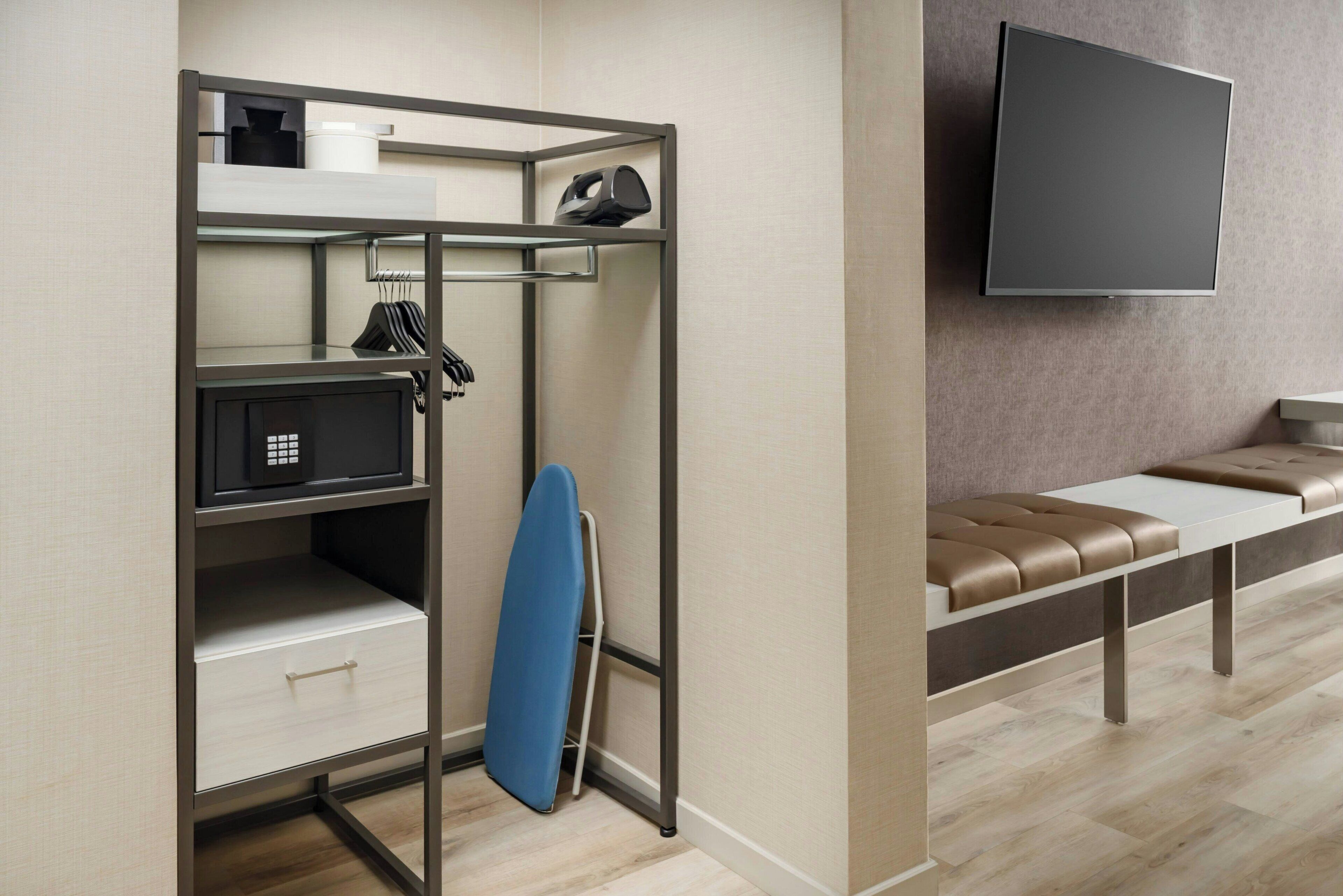 A compact room with a bed, a desk, a television, and a seating area.