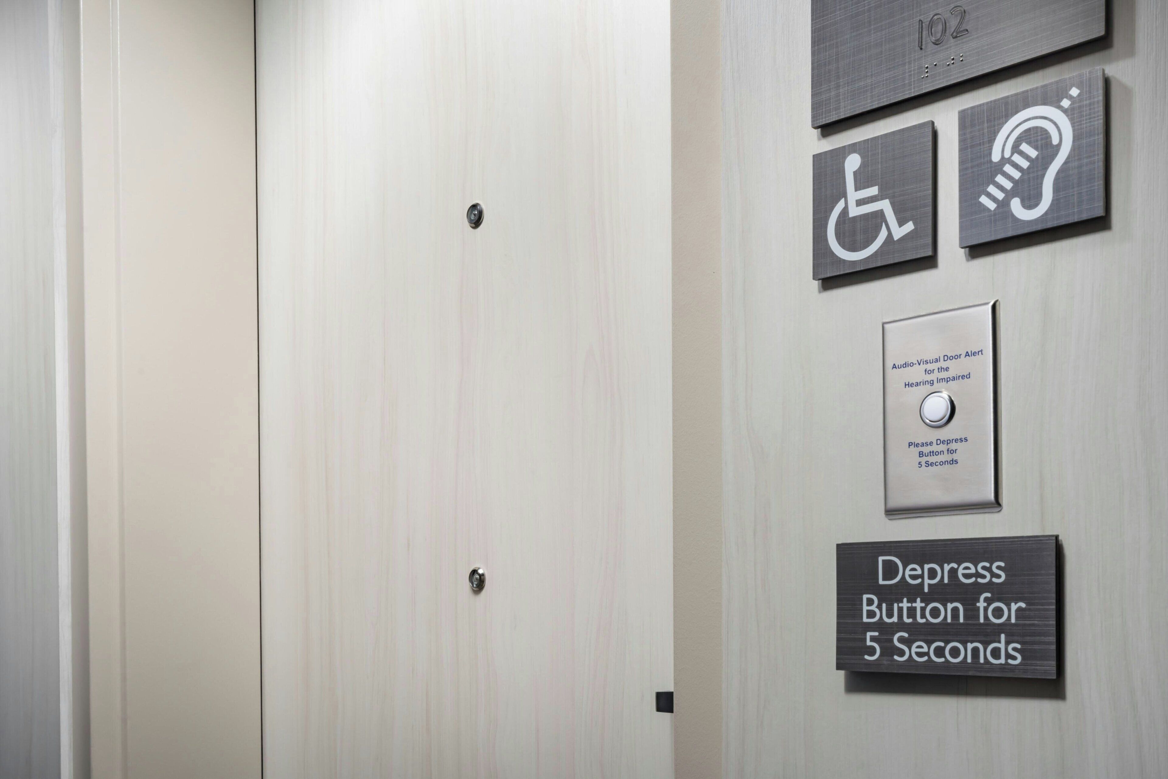 An elevator interior with a sign indicating a 5-second depress button for the hearing impaired.