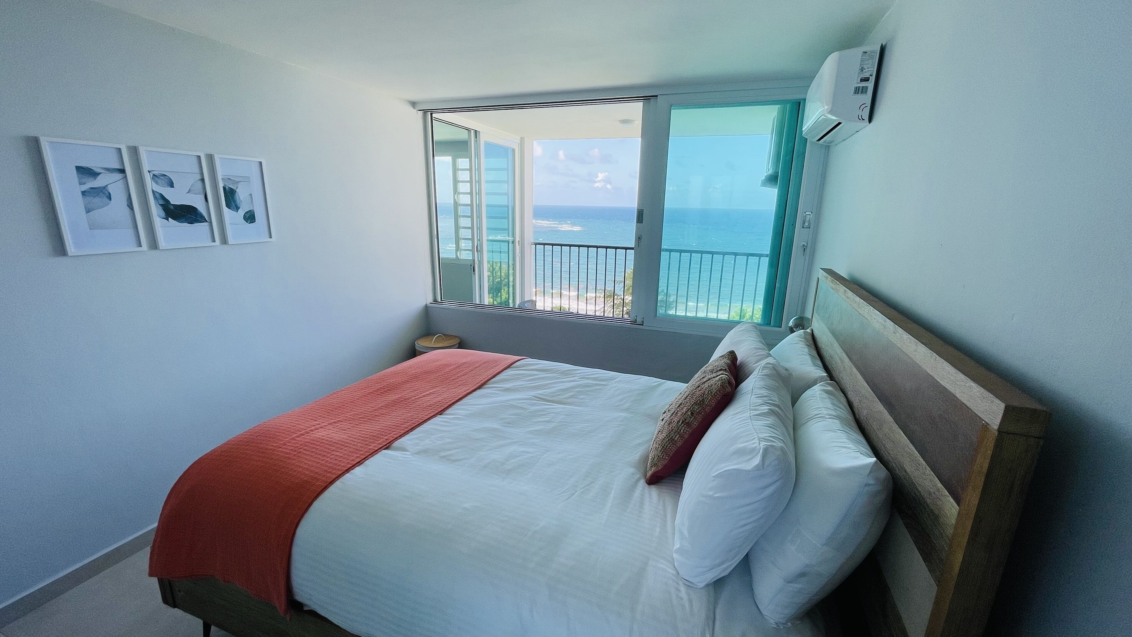 Ein Schlafzimmer mit Bett, Fenster mit Meerblick und einer Wand-Klimaanlage.