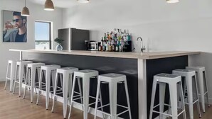 Una cucina moderna con un'area bar, sgabelli bianchi e diverse bottiglie sul bancone.