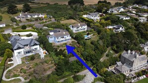 An aerial view of a residential area with houses, green lawns, and a blue arrow pointing to a specific location. - Fiddlers Green -  a holiday home that sleeps 12 guests  in 5 bedrooms (St Mawes)