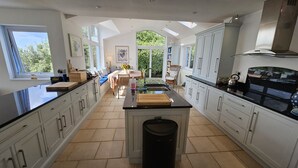 A spacious kitchen with high ceilings, large windows, and a central island. - Fiddlers Green -  a holiday home that sleeps 12 guests  in 5 bedrooms (St Mawes)