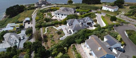 A coastal residential area with houses, a historic stone building, and a view of the sea.