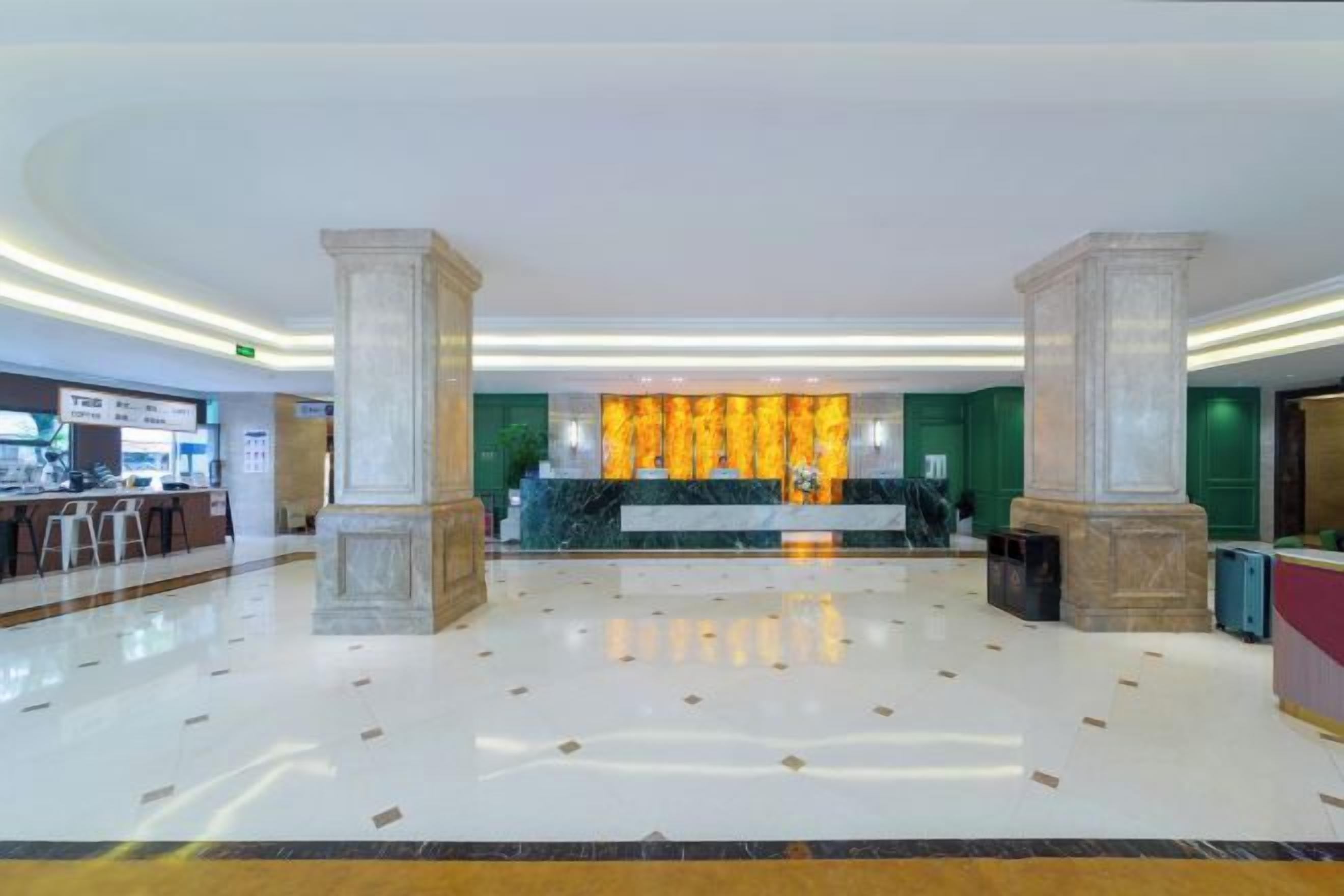 Un vestíbulo amplio con piso de mármol, una mesa de recepción y una pared decorativa con un diseño dorado.