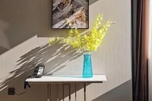 Un escritorio con un jarrón de flores amarillas, un teléfono y un cuadro en la pared.