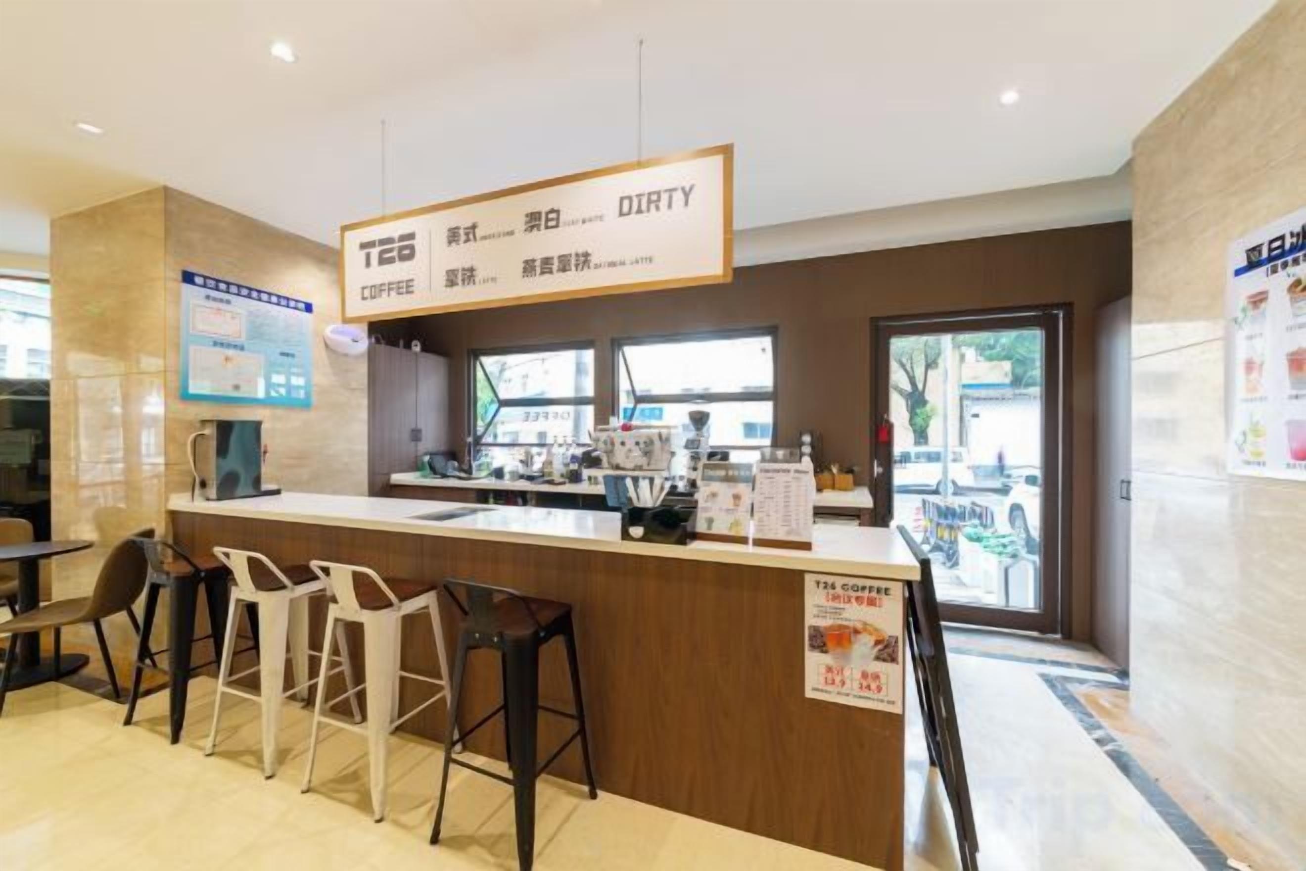 A coffee shop interior with a counter, stools, and a menu board.