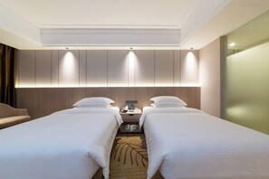 Una camera d'albergo con due letti, un comodino e una lampada a parete.
