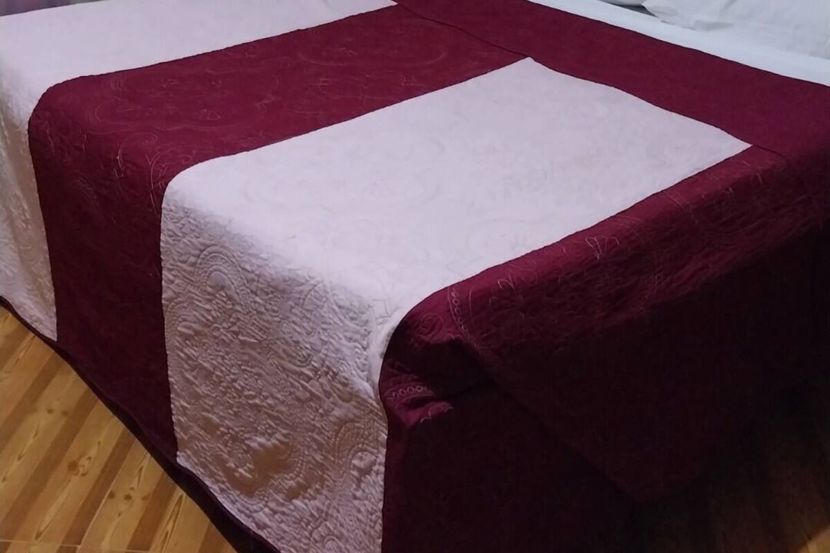 A room with two beds, each covered with a white and maroon bedspread.