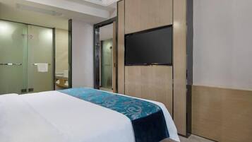 A hotel room with a bed, a flat-screen TV, a mirror, and a wardrobe.