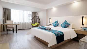 A hotel room with a large bed, a desk, a chair, and a hanging chair.