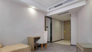 Una habitación de hotel moderna con un sofá color beige, un escritorio y una silla.