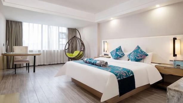 Habitación de hotel con cama, escritorio, silla y sillón colgante.