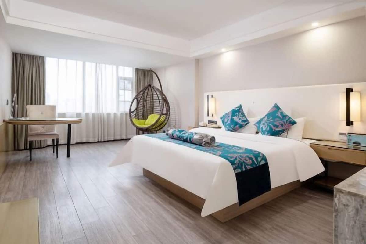 Una camera d'albergo con un letto, una scrivania, una sedia e una poltrona sospesa.