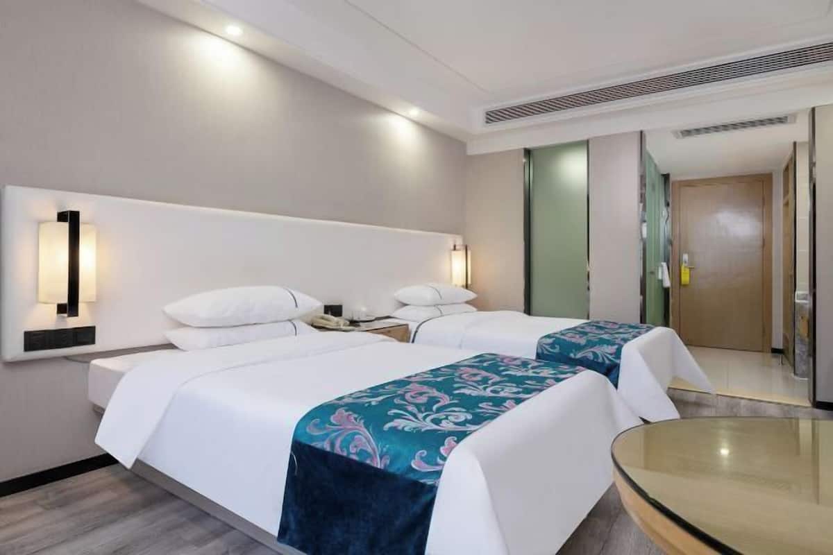 Camera d'albergo con due letti, un tavolino in vetro e un design moderno.