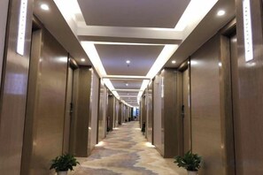 A hotel corridor with a carpeted floor, wooden doors, and recessed lighting. - Jindu Hotel (Guangzhou Railway Station Sanyuanli Subway Station Branch) (Guangzhou)