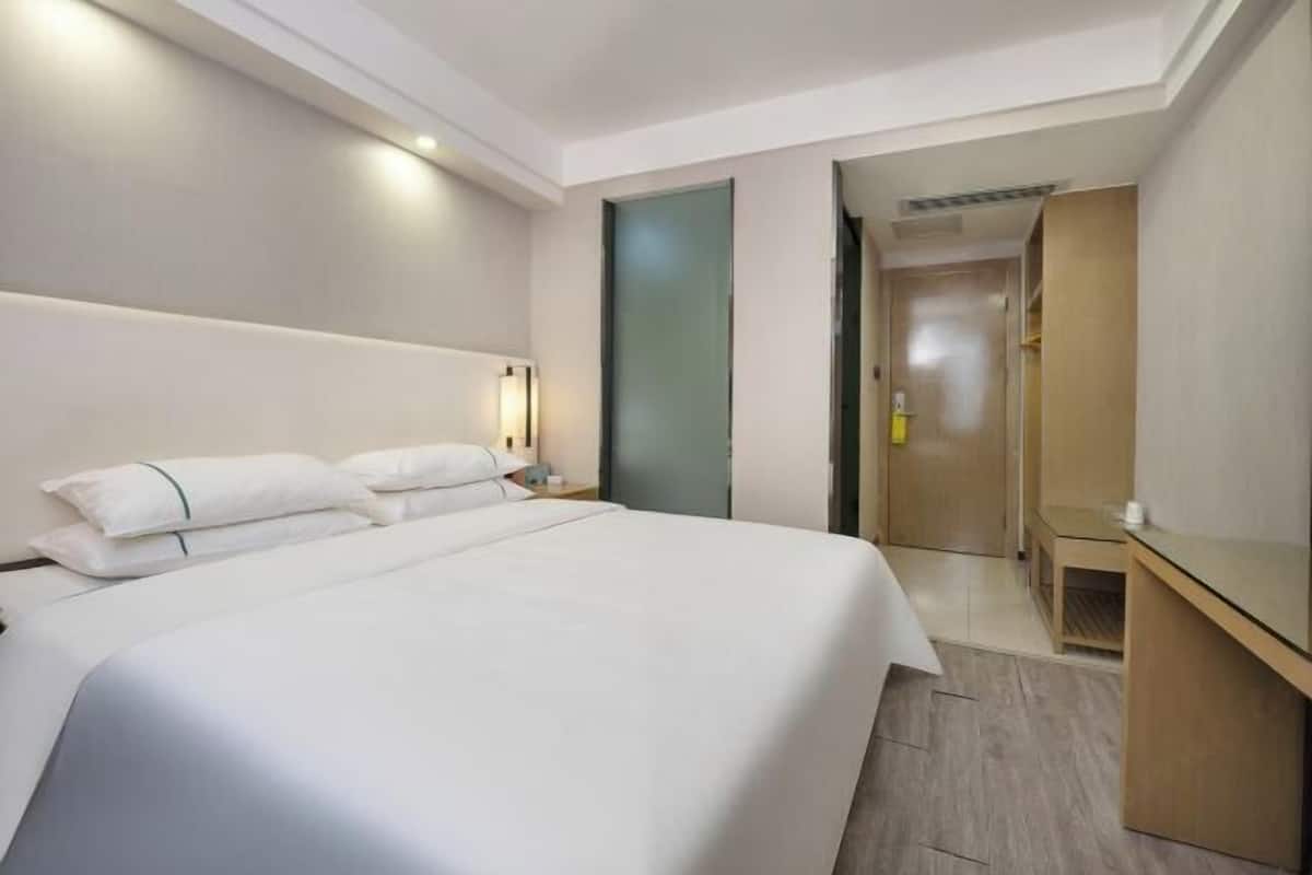 Una camera d'albergo moderna con un letto grande, comodini, un armadio e una porta che dà su un'altra stanza.