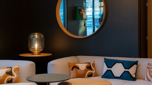 Un espace de détente moderne avec un canapé blanc, des tables rondes et un luminaire au plafond au design original.