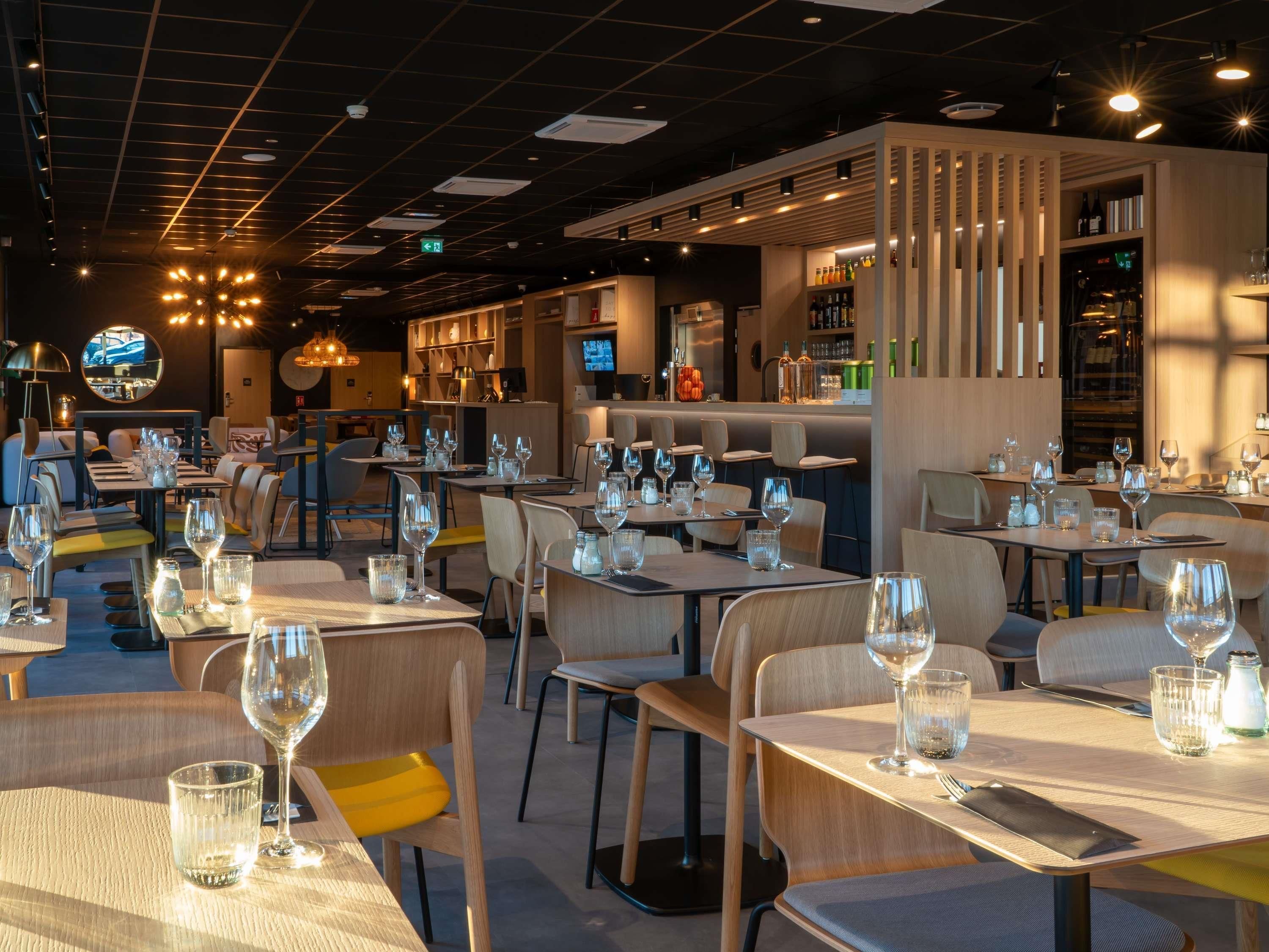 A restaurant interior with multiple dining tables, chairs, and a bar area.