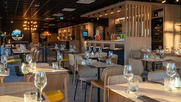 A restaurant interior with multiple dining tables, chairs, and a bar area.
