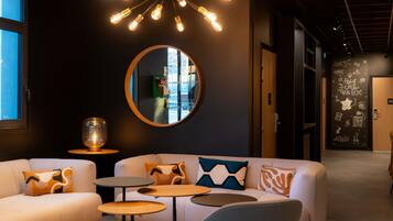 A modern interior with a white sofa, round tables, a large mirror, and a unique ceiling light fixture.